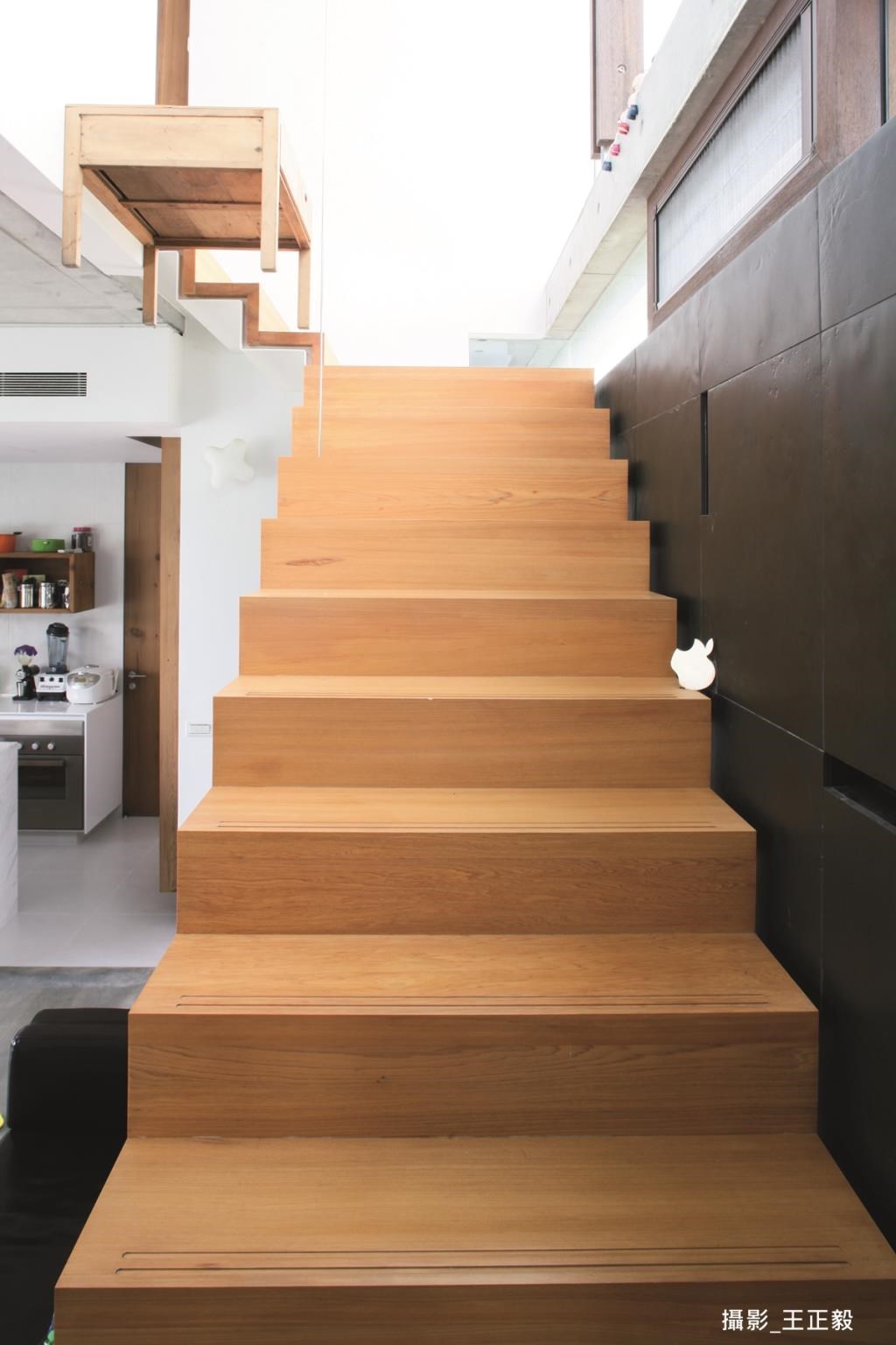 樓梯流暢地騰空向上伸展；轉折處，考慮小朋友的安全性問題，吊起一張木製小桌充當欄杆機能，成了趣味裝飾。