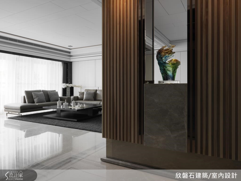 玄關以鋼構作設計，裡頭配置收納功能，運用木格柵門片和大理石交錯設計，強調大器感，底部則以明鏡材質做設計，營造出輕盈漂浮感。
