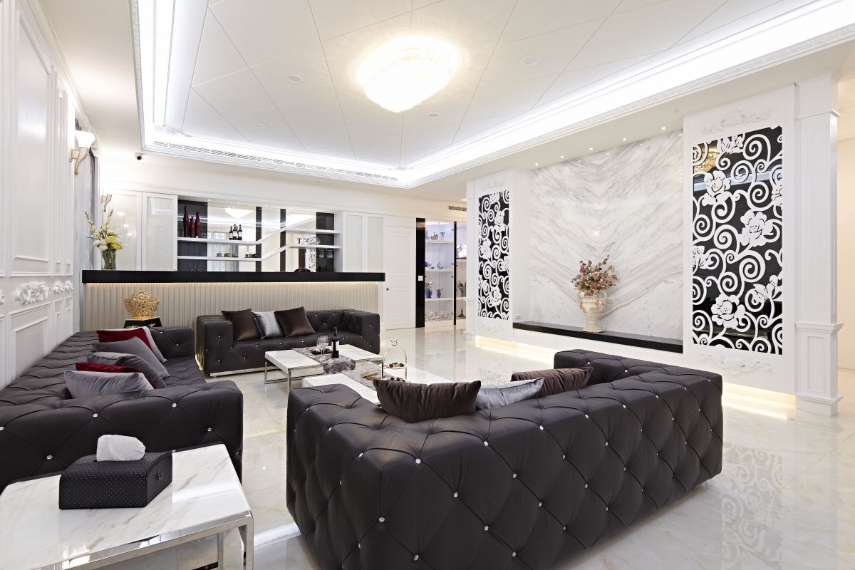 大理石電視牆略微後推，讓客廳空間變大，兩旁對稱的雕花門片，凸顯新古典的特色，一虛一實的設計，修整了樑柱問題，也提升了設計質感。