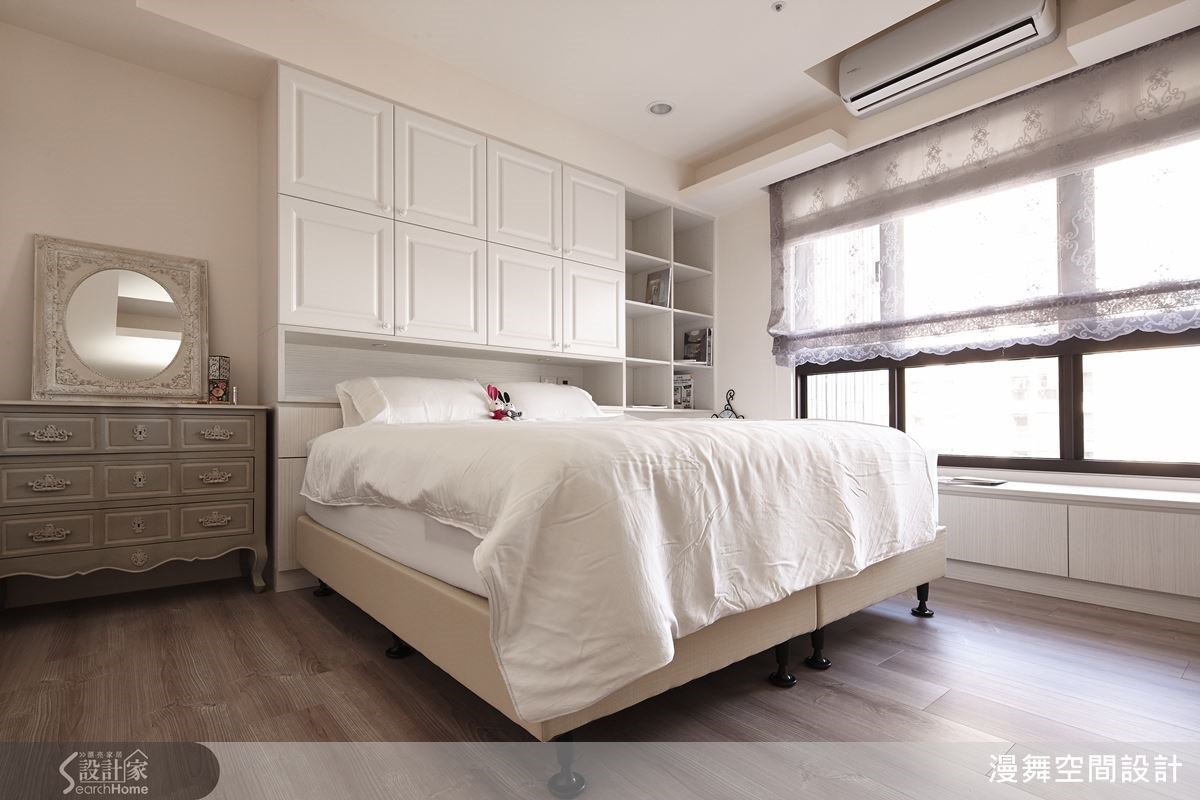 原先床頭背牆有壓樑的問題，設計師在下方規劃一整面的白色收納櫃化解。窗邊設計可收納的臥榻，一個可以放鬆看書的好所在。