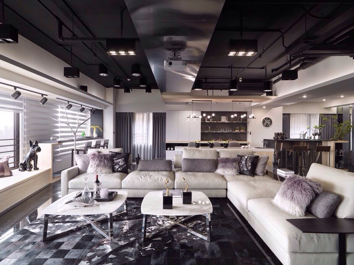 低彩度的客廳，以非制式組合的淺灰色皮沙發和跳色抱枕點綴，柔和的質感增添了空間的層次感。