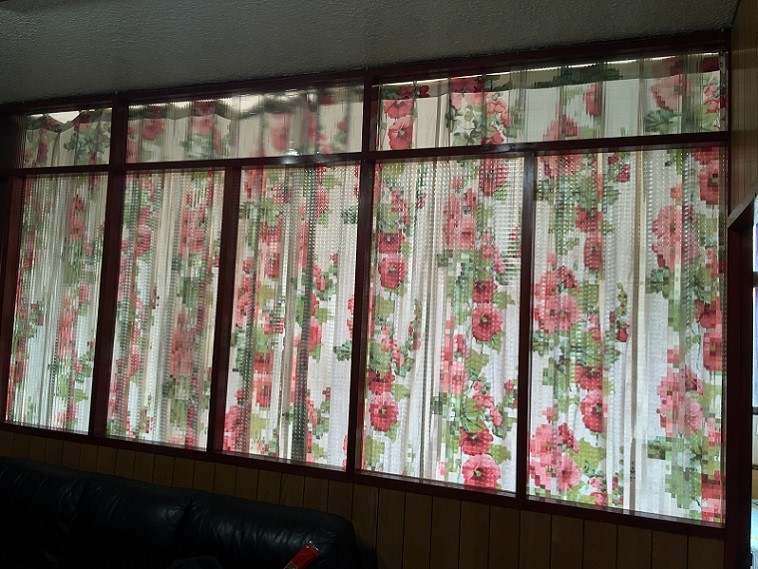 有嚴重西曬的長輩房，利用檜木玻璃隔間與簾幕為客廳作為遮擋陽光的工具，卻使客廳長年累月的壟罩在陰暗之中。