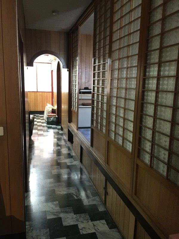 由客廳通往內部的走廊陰暗狹長，夾在曾遭蟻害的和室與次臥之間，成為光源的死角，也是育如設計師小時候晚上最怕經過的地方。