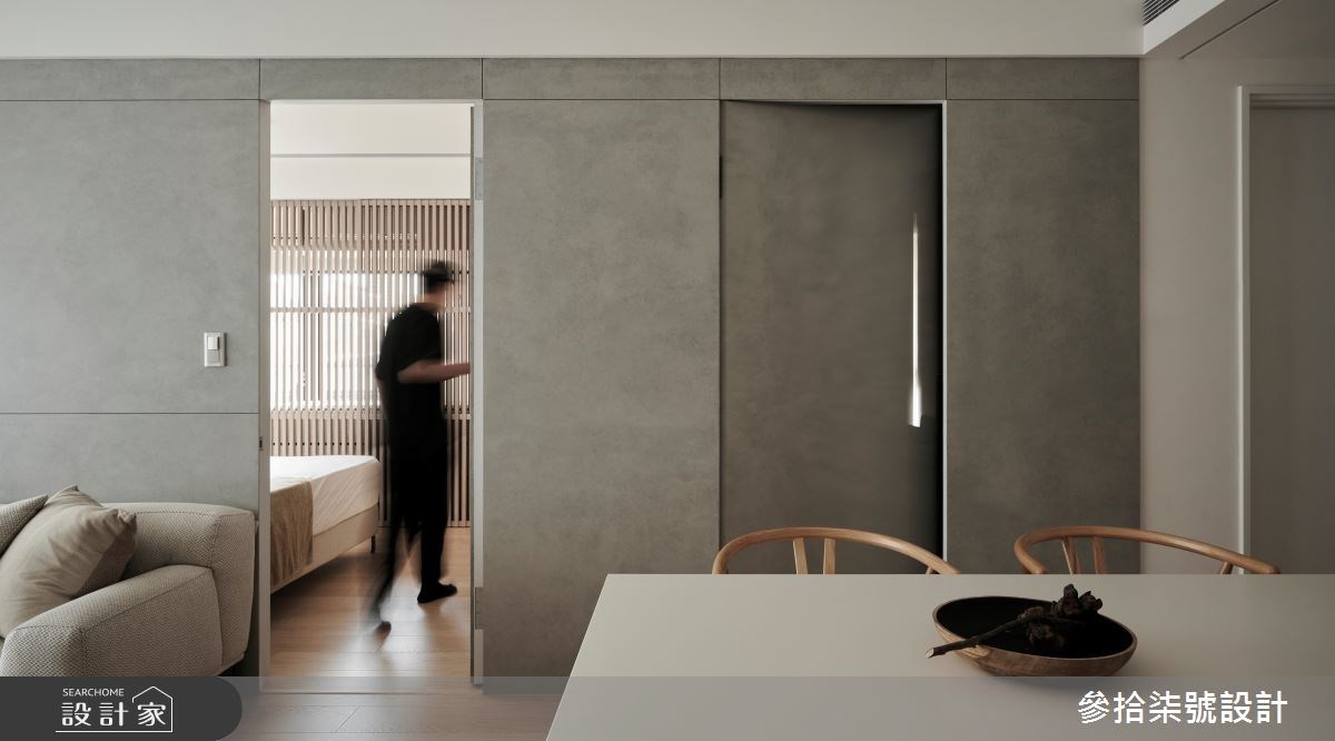 透過水泥色調和紋理的漫延,將多個動線入口整合於客廳背牆之中。>>看更多案例圖片