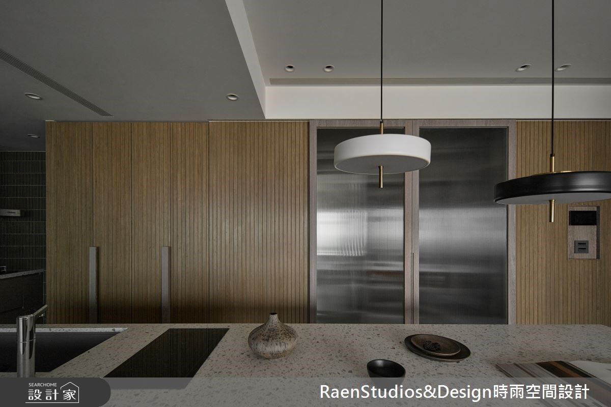 中島後方立面規劃直立式電器櫃,不用時將拉門拉上,即可維持俐落的視覺。