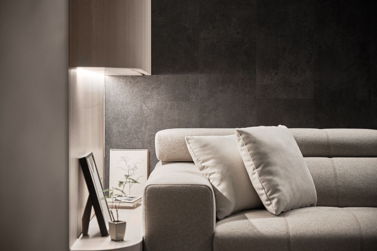 沙發背牆使用環保材質 SPC 壁板,呈現出深色質感,以卡扣拼貼的方式,創造出無縫的效果。