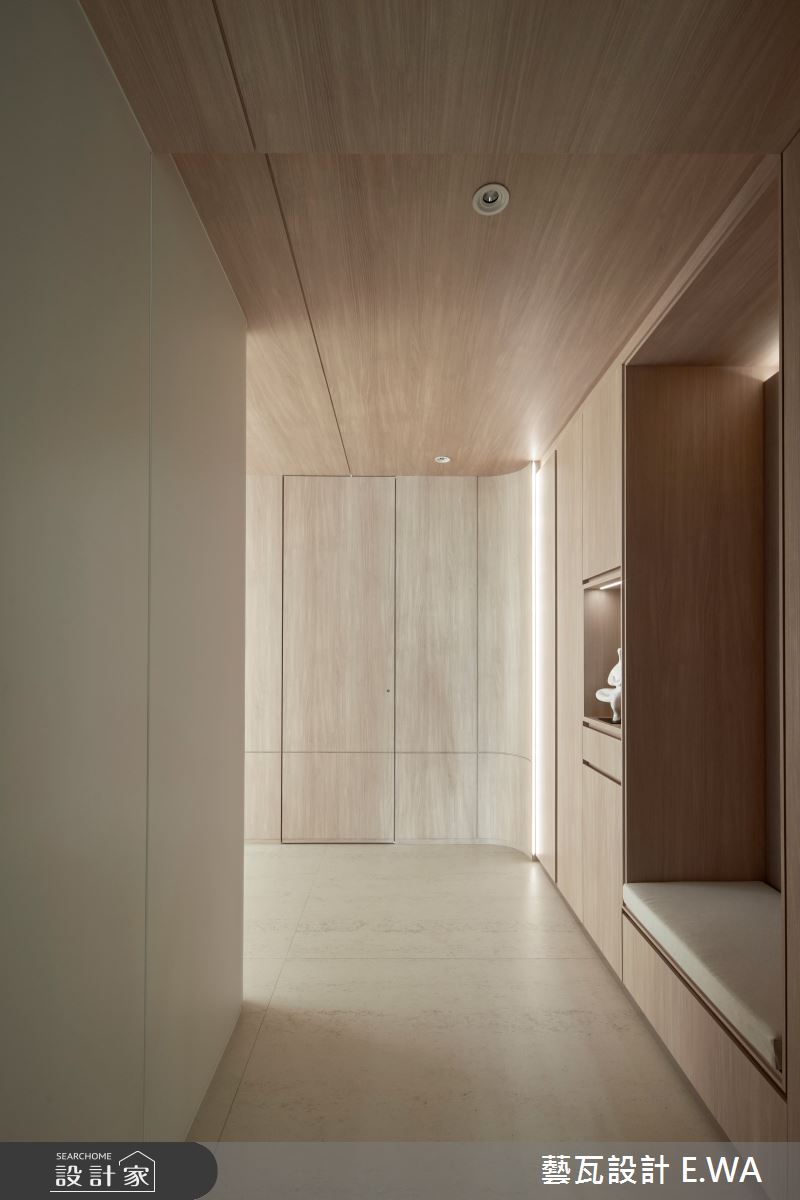 玄關以木紋包覆整個L型彎道的櫃體,打造隱藏儲藏室在其中,如同飯店的迎賓走道般精緻。