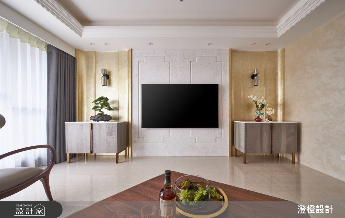 電視牆以晶鑽大理石鋪陳，下方撇開傳統的電視矮櫃，選擇分布於電視兩側的腰櫃，相襯著後方弧形金箔牆面的餔陳，呈現輕古典的氛圍。