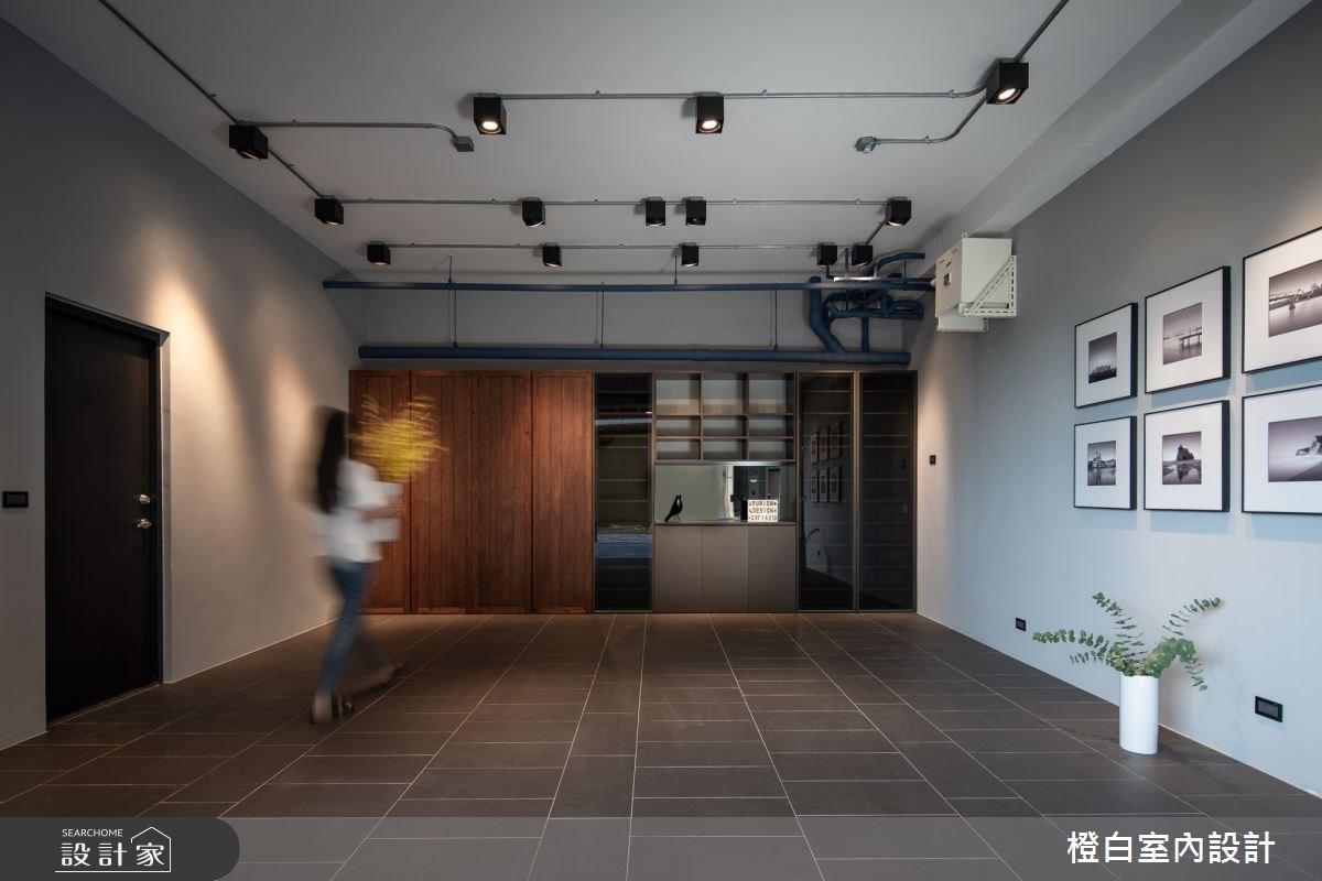 透天別墅大門一樓的車庫身兼儲藏室,外露式盒燈和管線,鋪設鐵灰地磚流露個性的工業風場景,結合暖感木質門片與金屬門片,美觀與機能兼具。