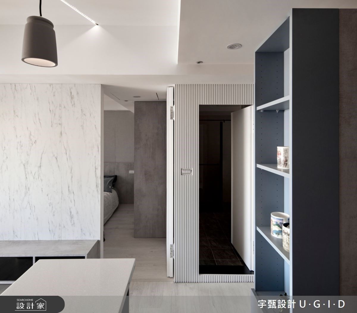 電視牆一旁的木格柵過度空間場域,隱藏了衛浴門片入口,上下左右的材質延伸,放大拓寬了空間尺度。