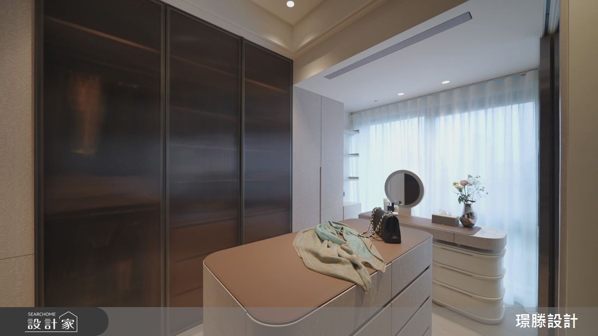 溫和溫暖的大地色調延續主臥室，更衣室內使用茶玻衣櫃門的設計，強化通透不厚重的選材技巧。