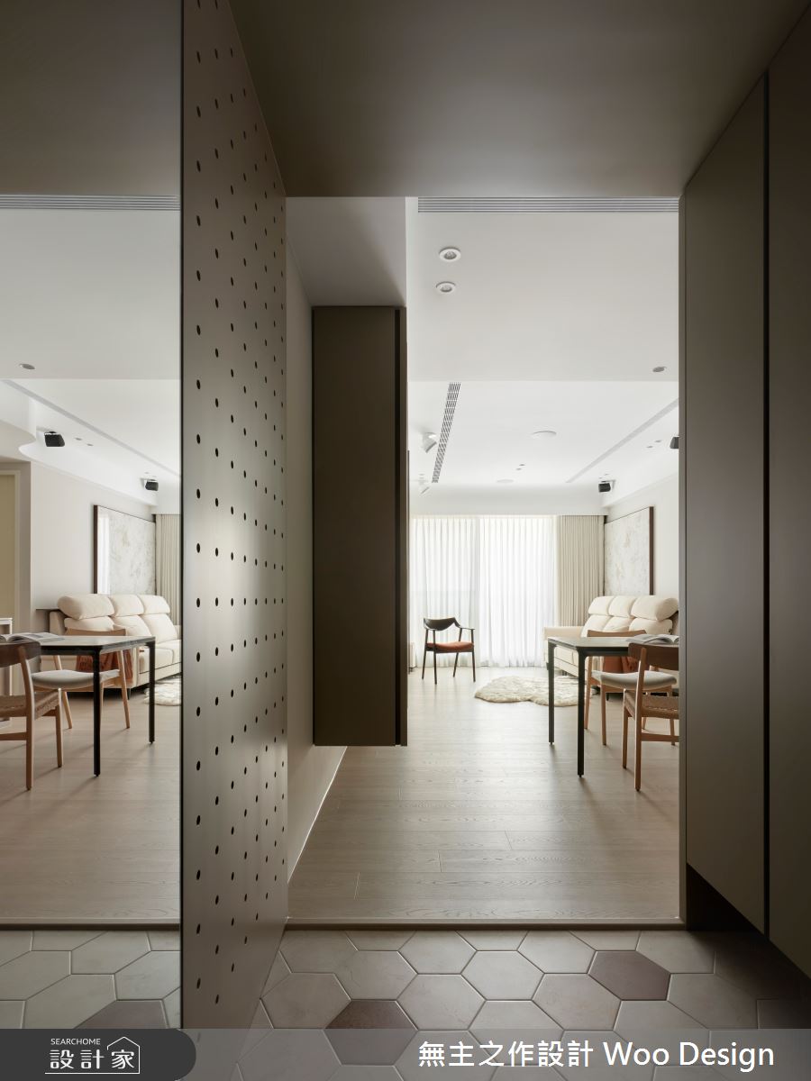 玄關以地磚鋪陳界定落塵區，搭配鏡面與洞洞板設計，巧妙結合穿戴、收納與整裝功能，豐富了出入的生活自理細節，同時營造出簡約有序的空間感。