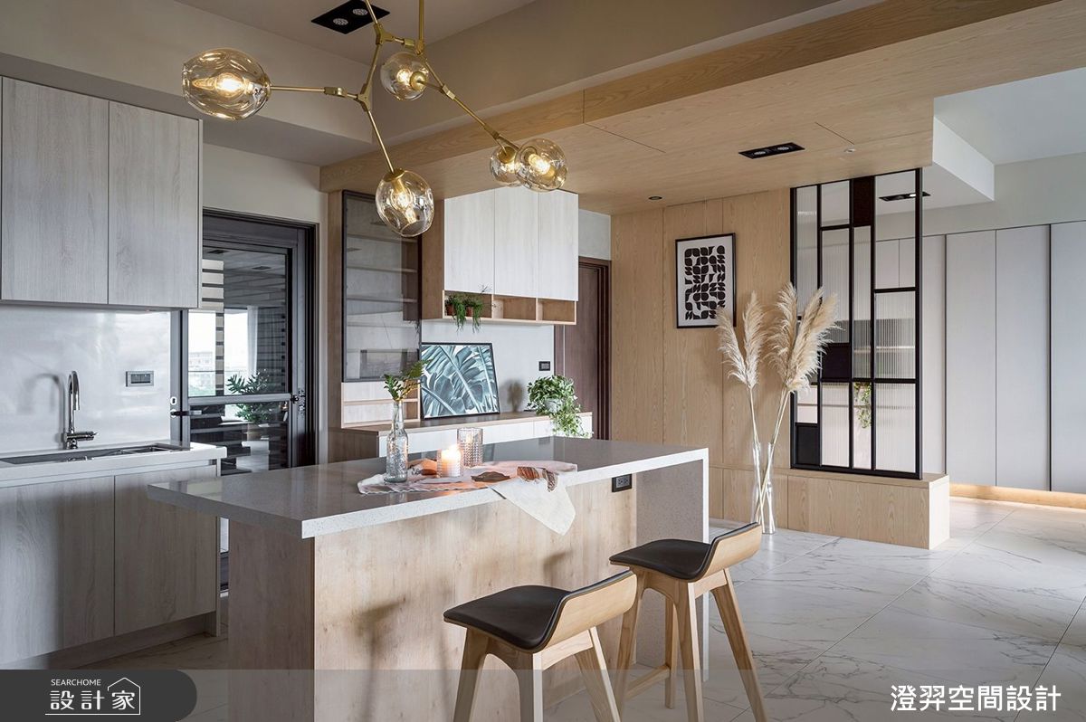 中島吧檯與懸吊燈組成餐廚核心，料理、備餐與小酌在此發生，開放式配置讓客廳與餐廚相互串聯，形成流暢的生活動線。