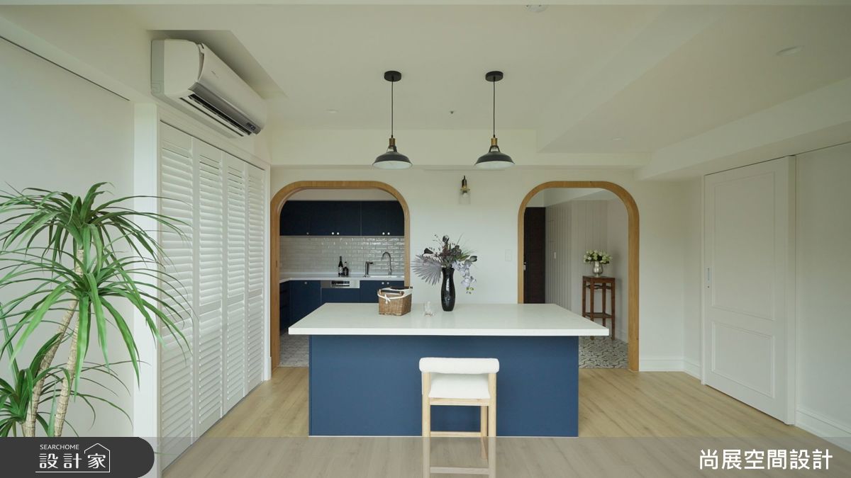 明亮藍色的廚具與木質門片對比鮮明，展現活力與個性；而內廚房的 L 型工作台與特殊磚面，則延伸出濃厚的美式風韻。