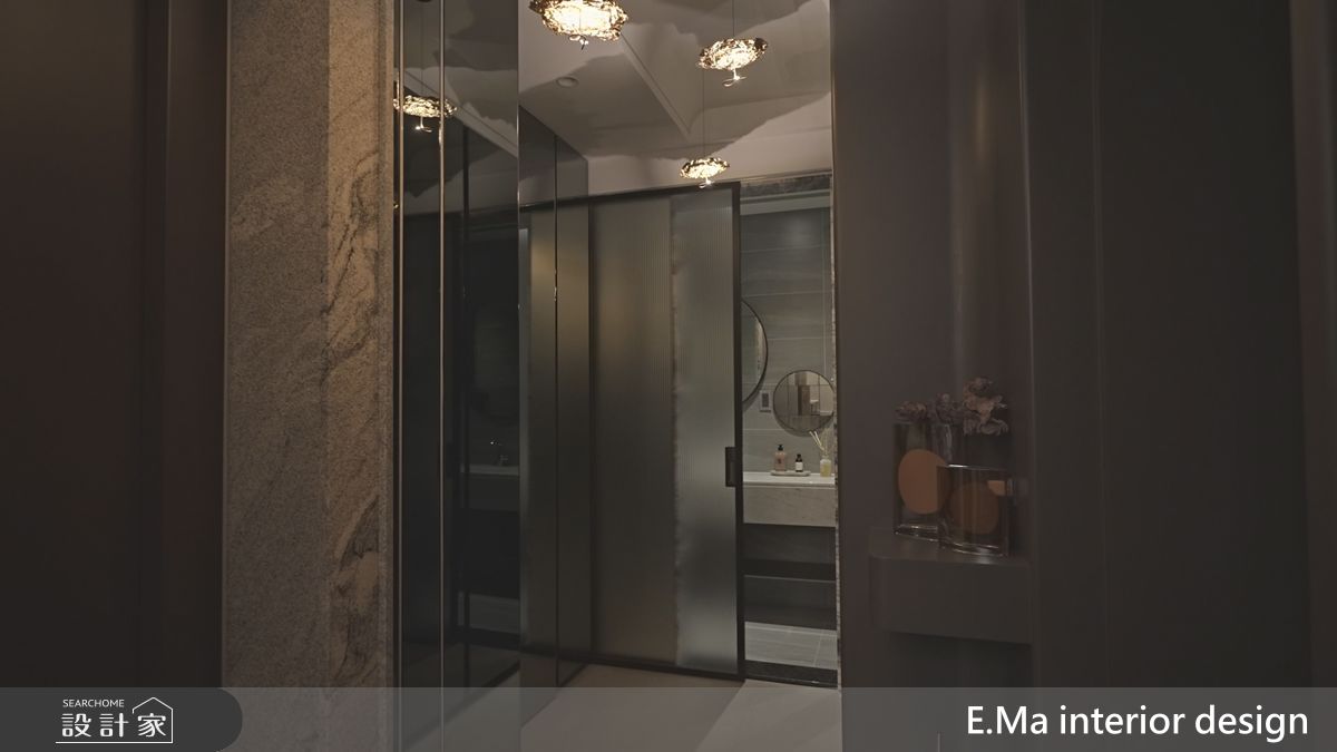 玄關鏡面加上玻璃，一道一道的揭開，即使隱藏的小客用衛浴，也能藉灰階材質與柔光塑造私密又溫潤的氛圍。