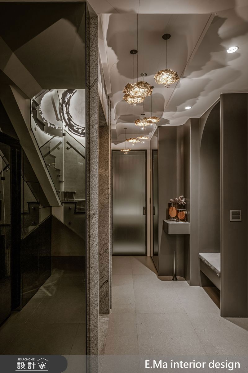 義大利原裝燈具與書法家藝術作品，營造出如藝廊般的玄關層次；玻璃扶手的樓梯則讓上下樓時能相互看見，增加互動。