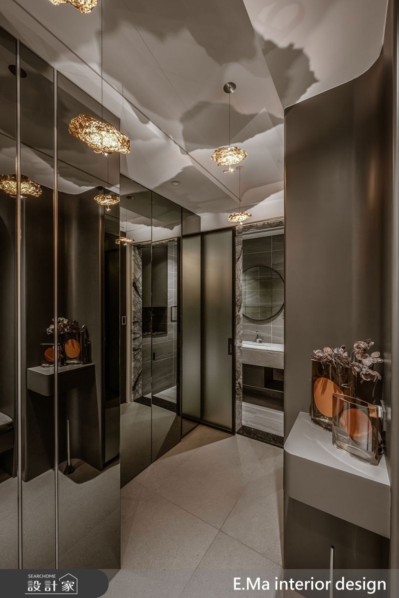 玄關鏡面加上玻璃，一道一道的揭開，即使隱藏的小客用衛浴，也能藉灰階材質與柔光塑造私密又溫潤的氛圍。