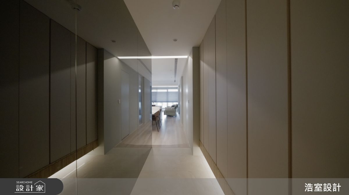 藉由灰鏡延伸視覺尺度，將長廊型玄關打造成開闊明亮的落塵空間。