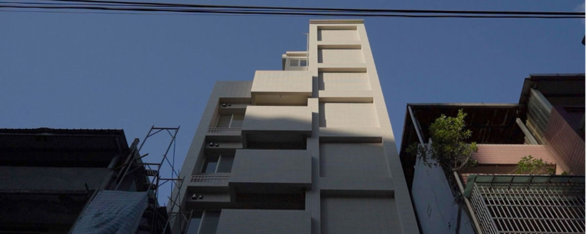 透過危老條例所改建的一棟極其細長的新大樓，矗立在兩棟舊平房之間。
