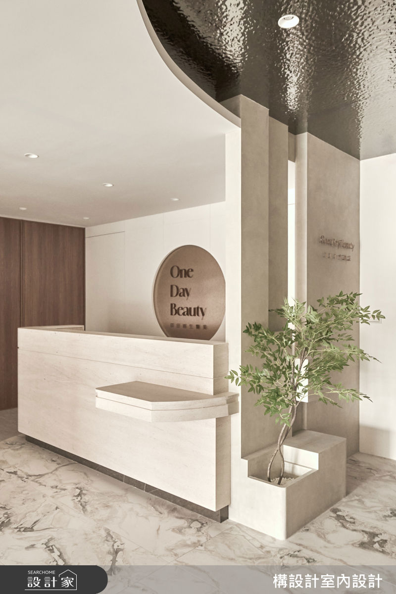 入口處以錯落的幾何量體結合綠意端景，搭配金屬水波紋天花板，構築出專屬高端客群的優雅質感