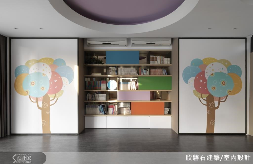 開放式書櫃上擺滿各式的兒童書籍,橘、粉、綠、藍四色層板則和兩旁牆面的彩色樹木相呼應。 開放式書櫃上擺滿各式的兒童書籍,橘、粉、綠、藍四色層板則和兩旁牆面的彩色樹木相呼應。