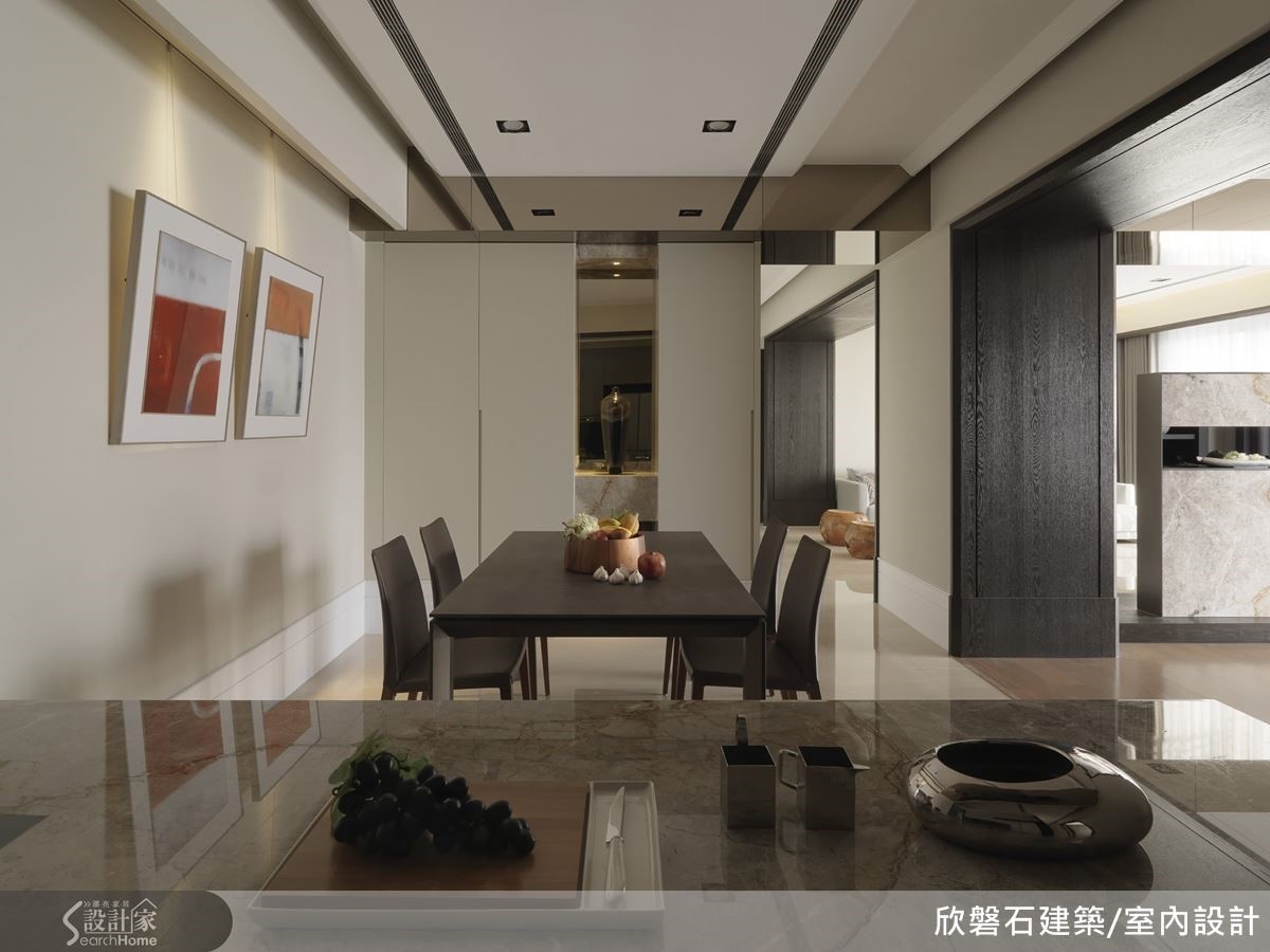 從廚房中島望向餐廳,天花勾勒的線條製造出空間深度。往下折、一深一淺的兩道垂板則隱藏了出風口、燈具與畫軌。 從廚房中島望向餐廳,天花勾勒的線條製造出空間深度。往下折、一深一淺的兩道垂板則隱藏了出風口、燈具與畫軌。