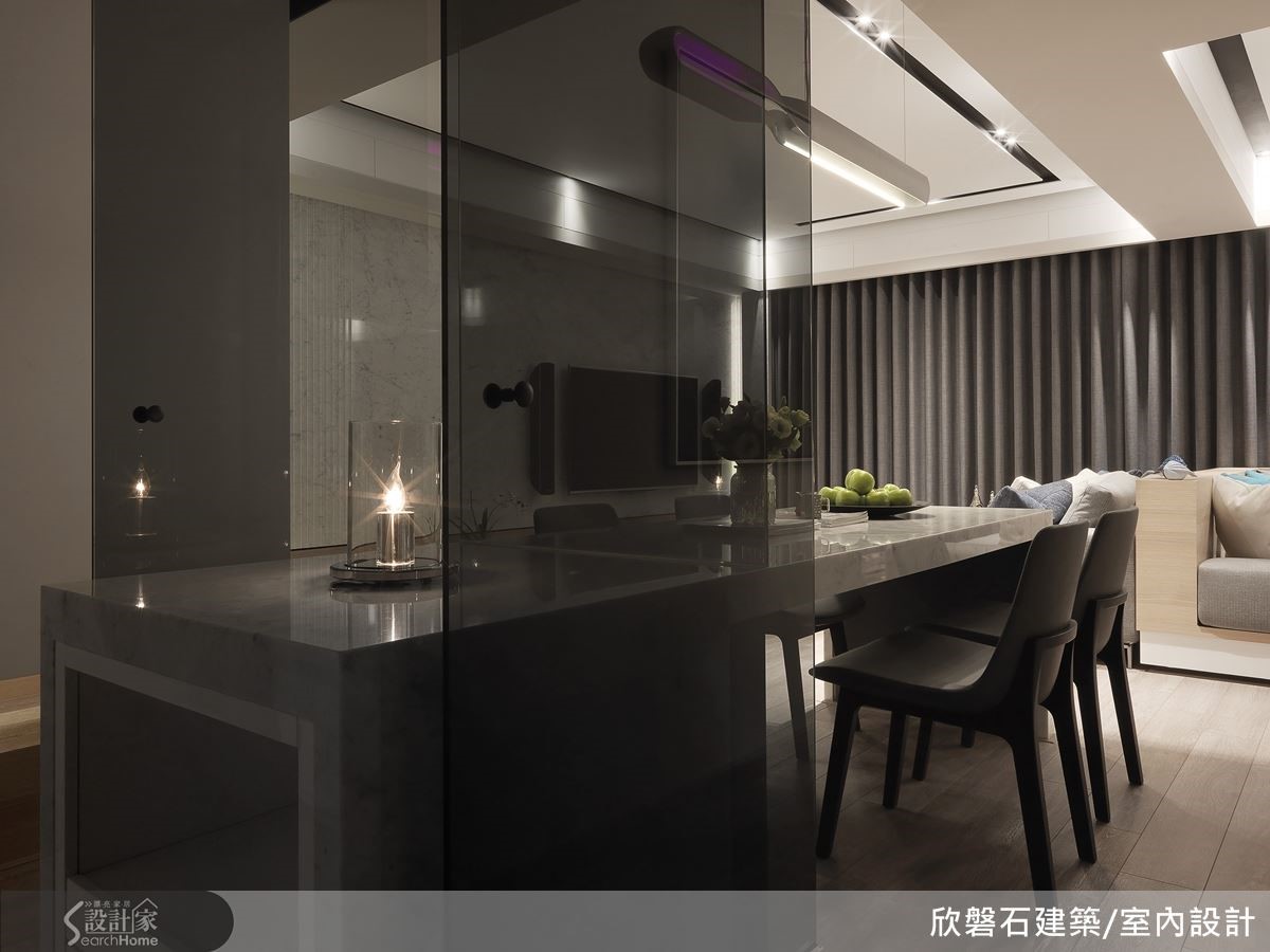 廚房以透明灰玻璃打造隔間牆與雙入口的門片,餐桌則穿過灰玻隔間進入廚房,化為備餐檯。 廚房以透明灰玻璃打造隔間牆與雙入口的門片,餐桌則穿過灰玻隔間進入廚房,化為備餐檯。