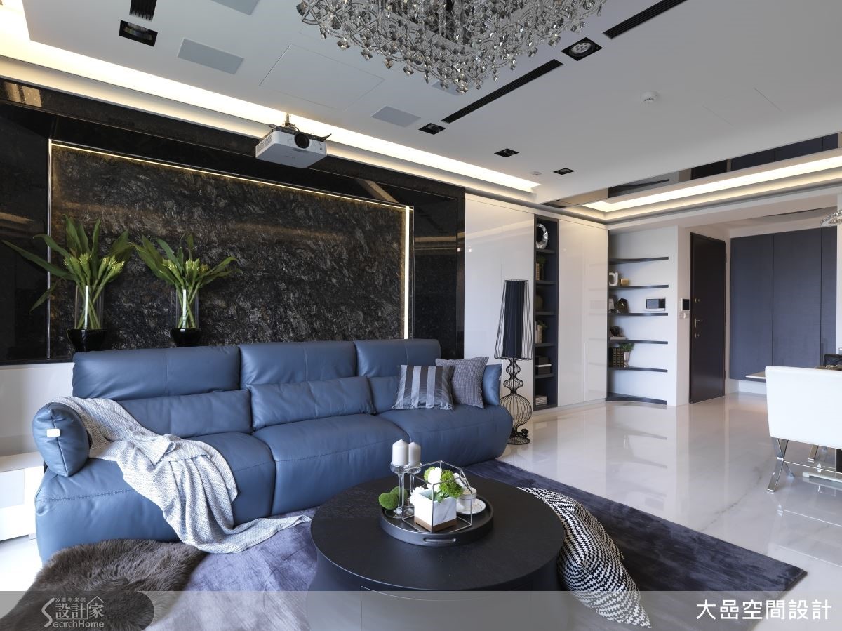洗鍊沉穩的灰色沙發,從容地坐落在深黑結晶大理石背牆前,堆疊客廳層次感,框線語彙與天花間接照明互相對應。 洗鍊沉穩的灰色沙發,從容地坐落在深黑結晶大理石背牆前,堆疊客廳層次感,框線語彙與天花間接照明互相對應。