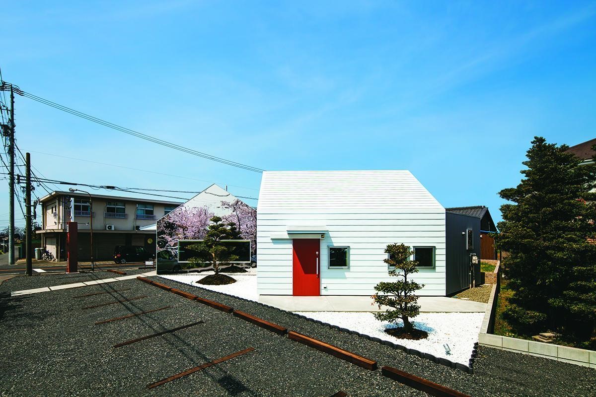 設計單層的傳統木屋造型建築,以便融合當地建築高度,外牆以鋼材電鍍成純白色與淺粉色的櫻花相互輝映,並以白色碎石界定建築腹地範圍且栽種茶樹,因此在冬季造訪咖啡館的顧客,也能提前欣賞到茶樹綻放的美麗紅花,為純樸的小鎮增添一隅風景。 設計單層的傳統木屋造型建築,以便融合當地建築高度,外牆以鋼材電鍍成純白色與淺粉色的櫻花相互輝映,並以白色碎石界定建築腹地範圍且栽種茶樹,因此在冬季造訪咖啡館的顧客,也能提前欣賞到茶樹綻放的美麗紅花,為純樸的小鎮增添一隅風景。